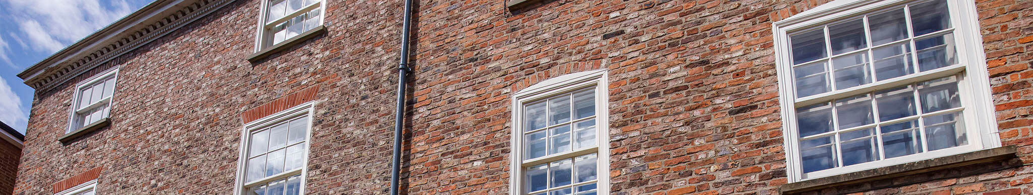 A brick building with white sash windows and blue sky above.